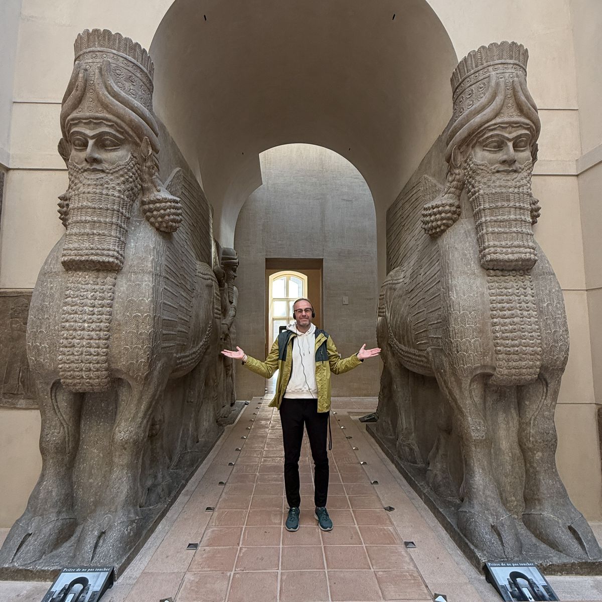 Artur Jakucewicz between two giant lamassu in the Cour Khorsabad during the Another Louvre guided tour